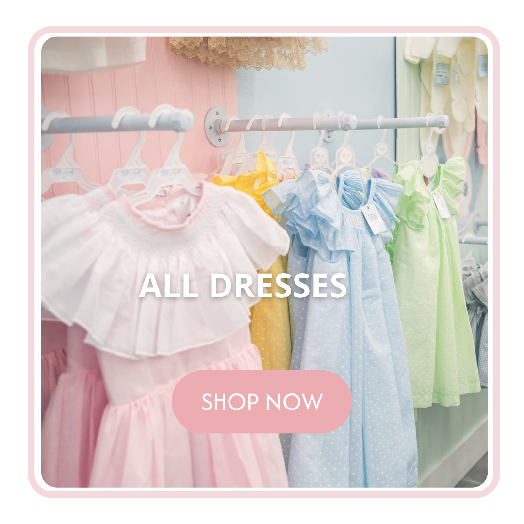 Colorful boutique girls dresses hanging on a retail clothing rack in pink, blue, and green pastel shades.